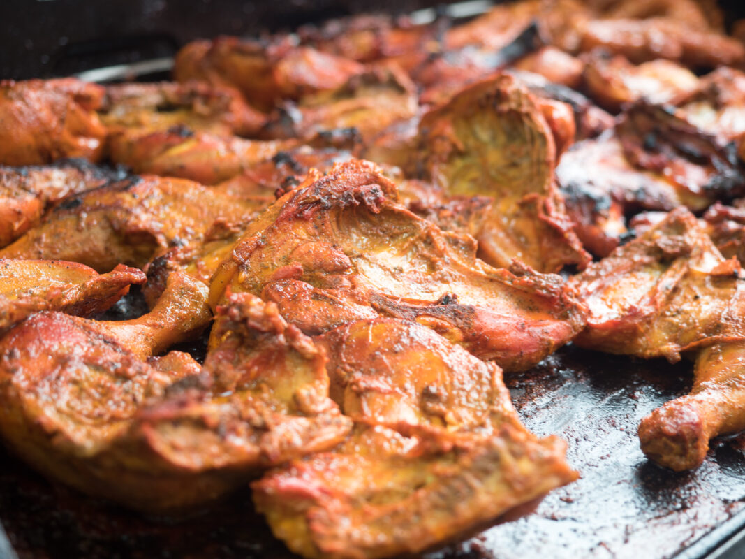 Lots of pieces of sri lankan tandoori chicken cooking on a griddle pan