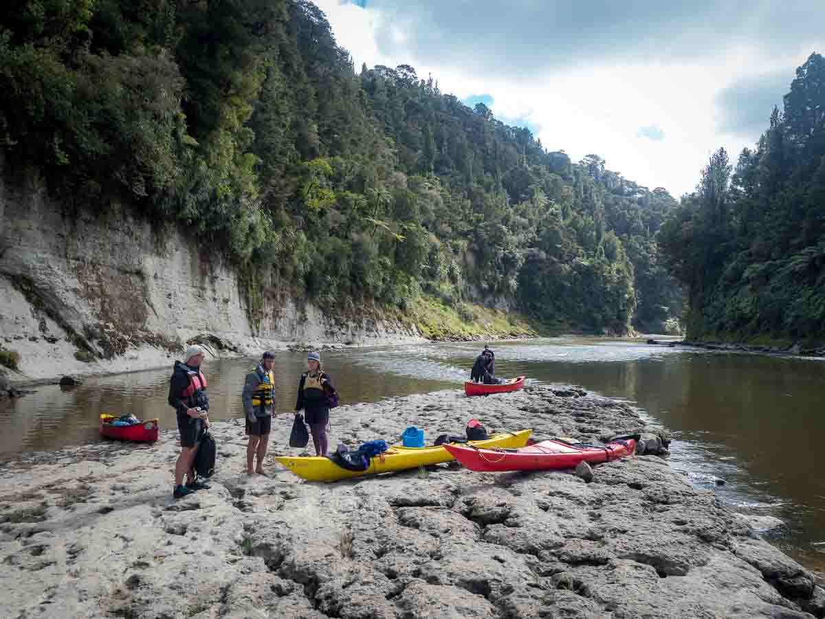 Paddlers hauling canoes onto a stony landing on the Whanganui River