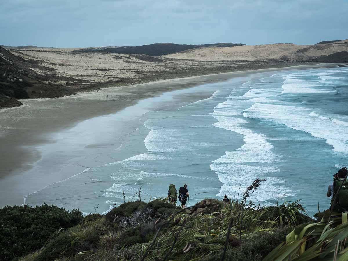 Hikers descending towards Te Werahi Beach on the Te Paki Coastal Track