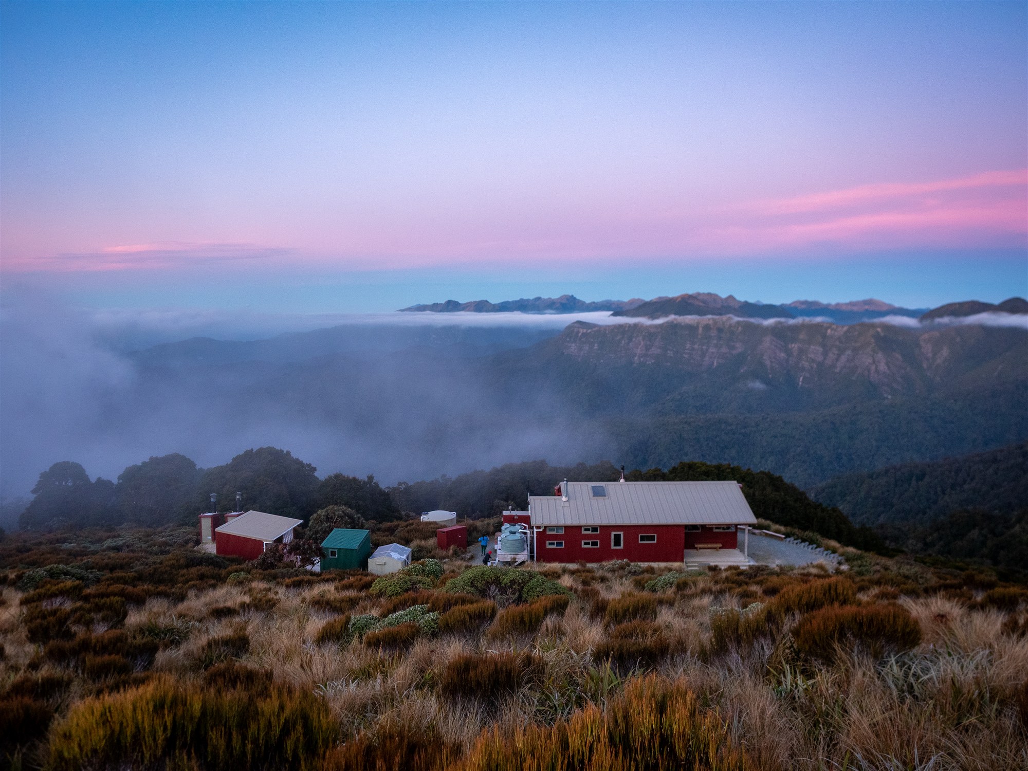 Moonlight Tops Hut beneath pink evening clouds on the Paparoa Track
