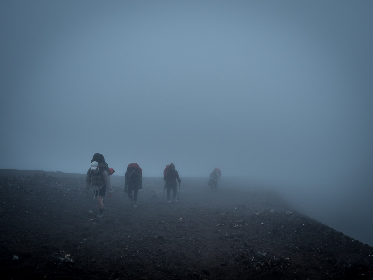 Trampers walking through thick cloud and rain on the Tongariro Northern Circuit