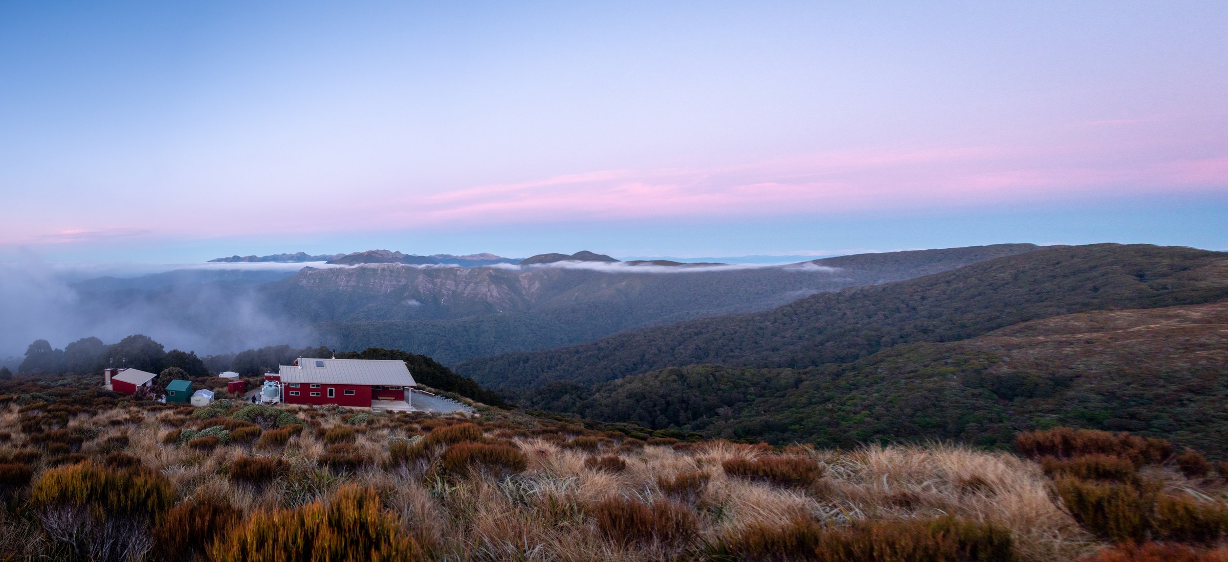Moonlight Tops Hut beneath a wide pink evening sky